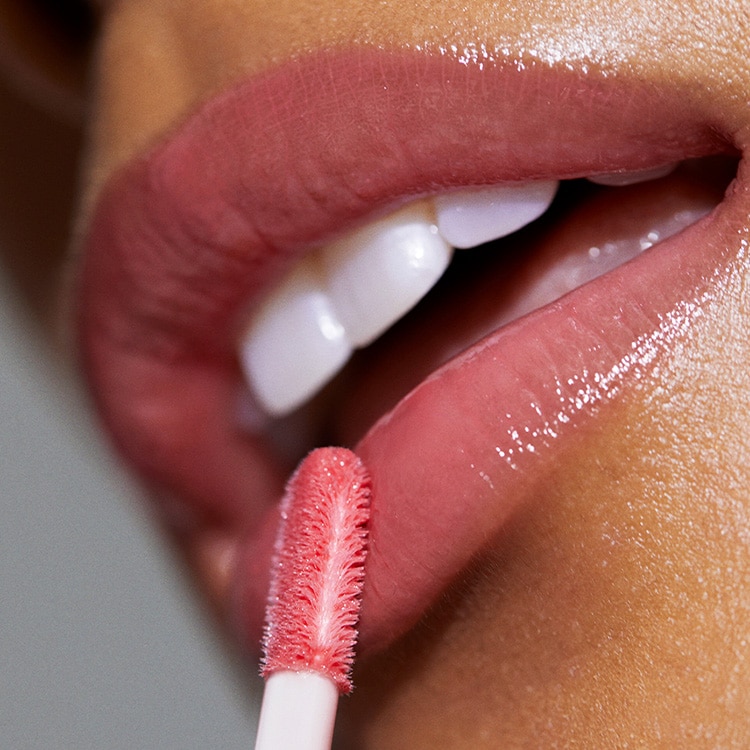 Close up of model applying Crushed-Oil Infused Gloss to lips